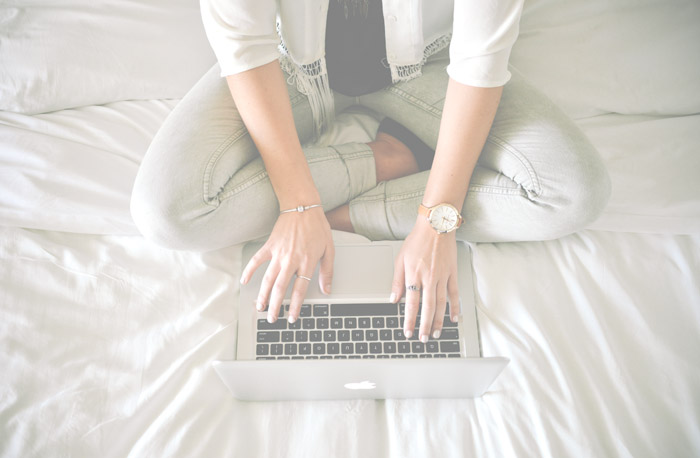 Wonans Hands With Jewelry Typing On Laptop Sitting On A Bed Website Design Copy Writing with ease